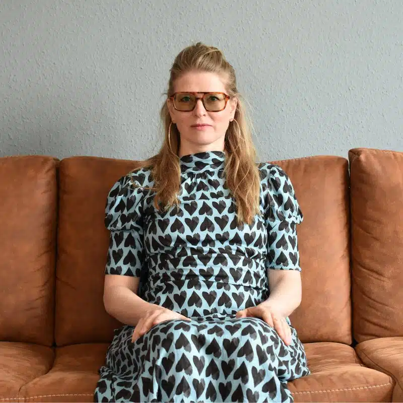 Porträt von Sylvia Lee auf einem braunen Sofa
